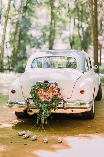 Bumper of retro car with just married sign and cans attached.